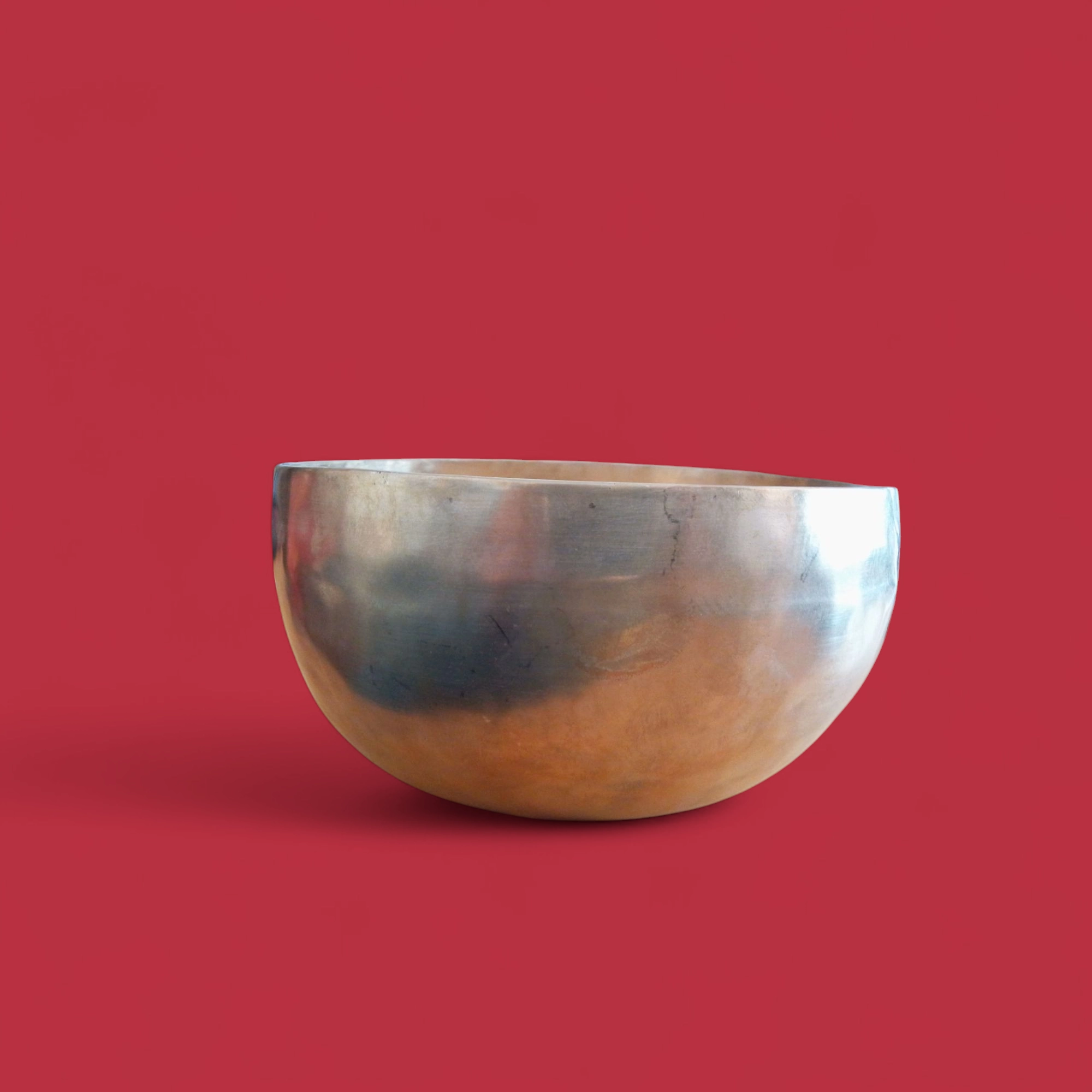 La Campana Tibetana Nota RE(D) 4 292 HZ - R121/C, caratterizzata da una superficie liscia e riflettente color marrone dorato, è esposta su uno sfondo rosso uniforme.